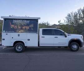 Two North Star Outdoor Lighting service trucks parked side by side