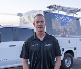 Todd Meyer of North Star Outdoor Lighting in front of two branded service trucks
