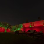 Backyard lit in red and green with color-changing LED landscape lighting