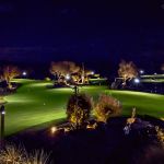 Golf course putting green and desert landscaping lit at night under a blue evening sky