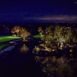Golf course lake and uplit trees at night reflected in the water