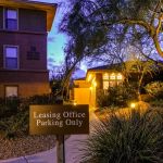 Apartment building and leasing office parking sign lit at dusk