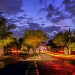 Apartment community entrance drive lit at dusk with light trails from passing cars