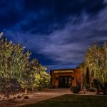 Lit contemporary building entrance at dusk with uplit desert planting