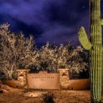 Pinnacle Peak Place stone entry monument lit at night beside an uplit saguaro