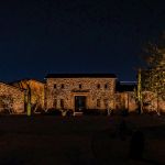Stone-faced desert home lit at night with saguaro cactus uplit in the yard