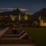 Tiered brick water feature lit at night beside a lawn, with mountains behind