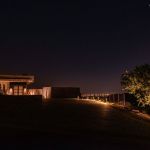 Paver drive lit at night leading to a contemporary desert home