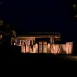 Contemporary home entrance lit at night with uplit agave against the walls