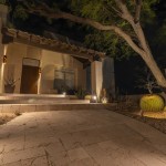 Lit covered entry and flagstone driveway at night with a barrel cactus