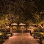 Paver walkway leading to a lit arched-window building entrance at night