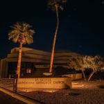 Lit exterior of St. George Antiochian Orthodox Church with an uplit palm at night