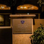 Lit Legacy Ballroom dedication plaque on a stone pillar at night
