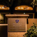 Legacy Ballroom dedication plaque lit at night with the building windows behind
