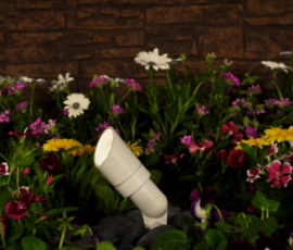Beige adjustable bullet uplight staked in a flower bed at night
