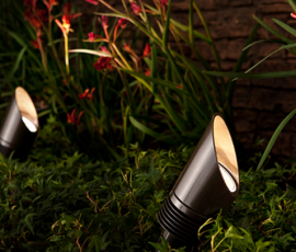 Dark bronze bullet uplight staked in a garden bed at night